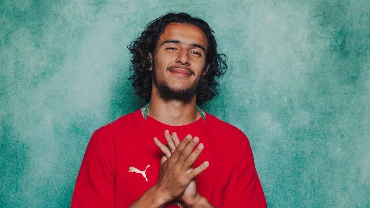 Player in red jersey smiling with hands clasped