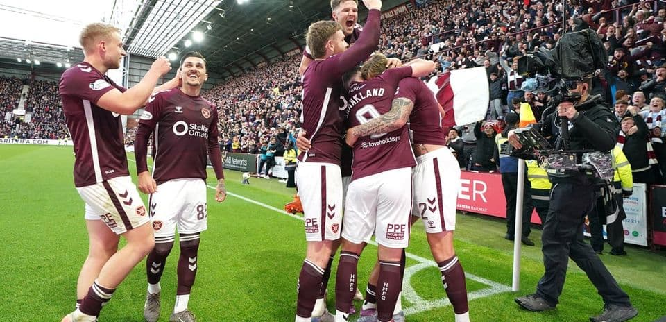 Hearts players celebrating a goal with fans in background