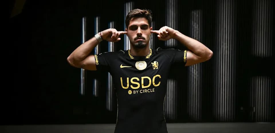 Player in black jersey poses with fingers in ears