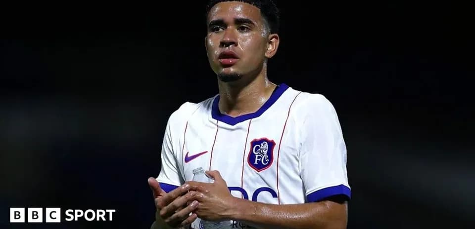 Player in white jersey holding water bottle on pitch