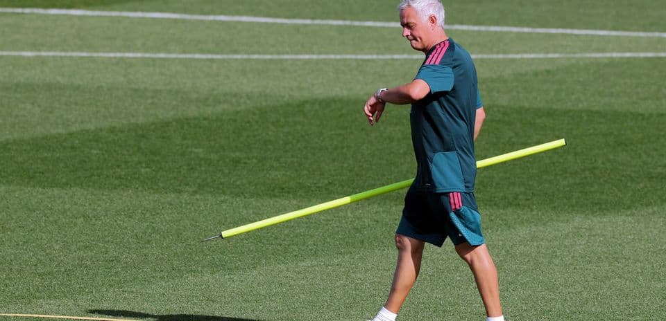 Coach walking on training pitch with equipment