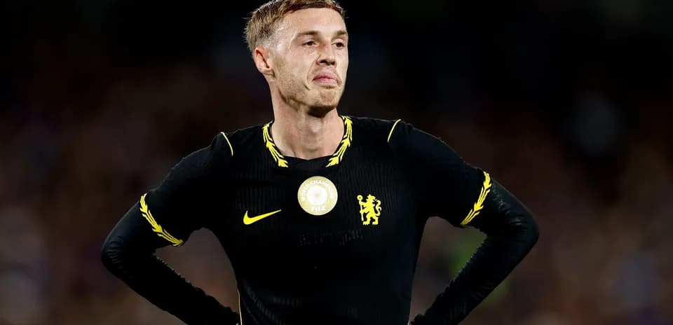 Player in black kit with yellow accents, looking concerned