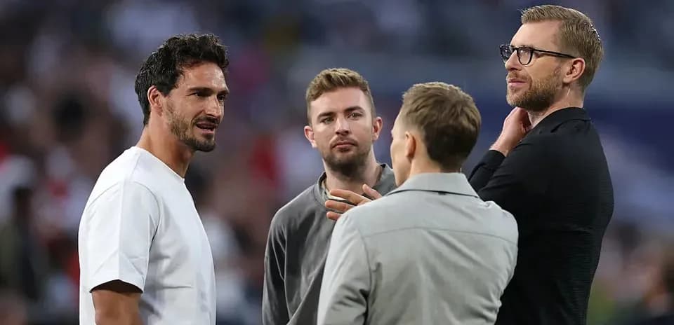 Four men conversing on the field before a match