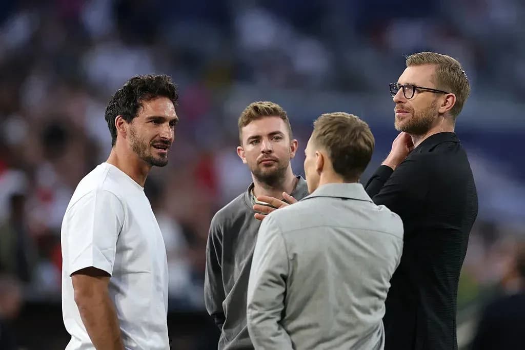 Four men conversing on the field before a match