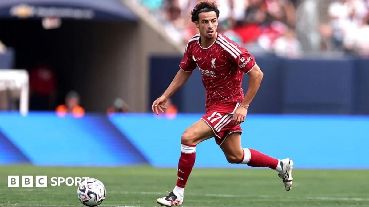 Player in red kit dribbling the ball on field