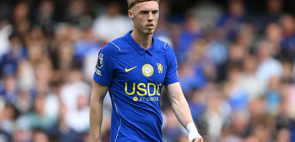 Player in blue Chelsea kit walking on the pitch