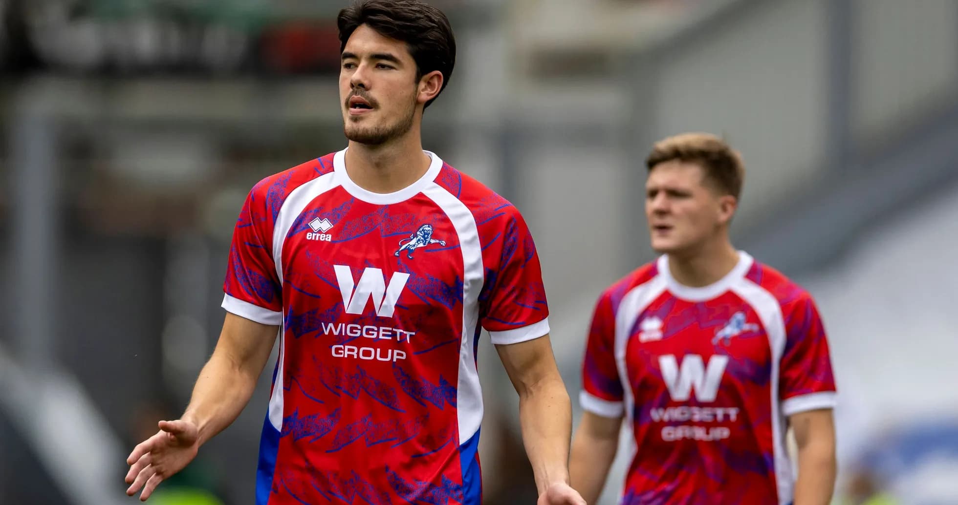 Players in red and blue team kits walking on field