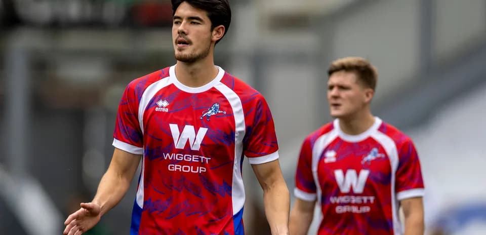 Players in red and blue team kits walking on field
