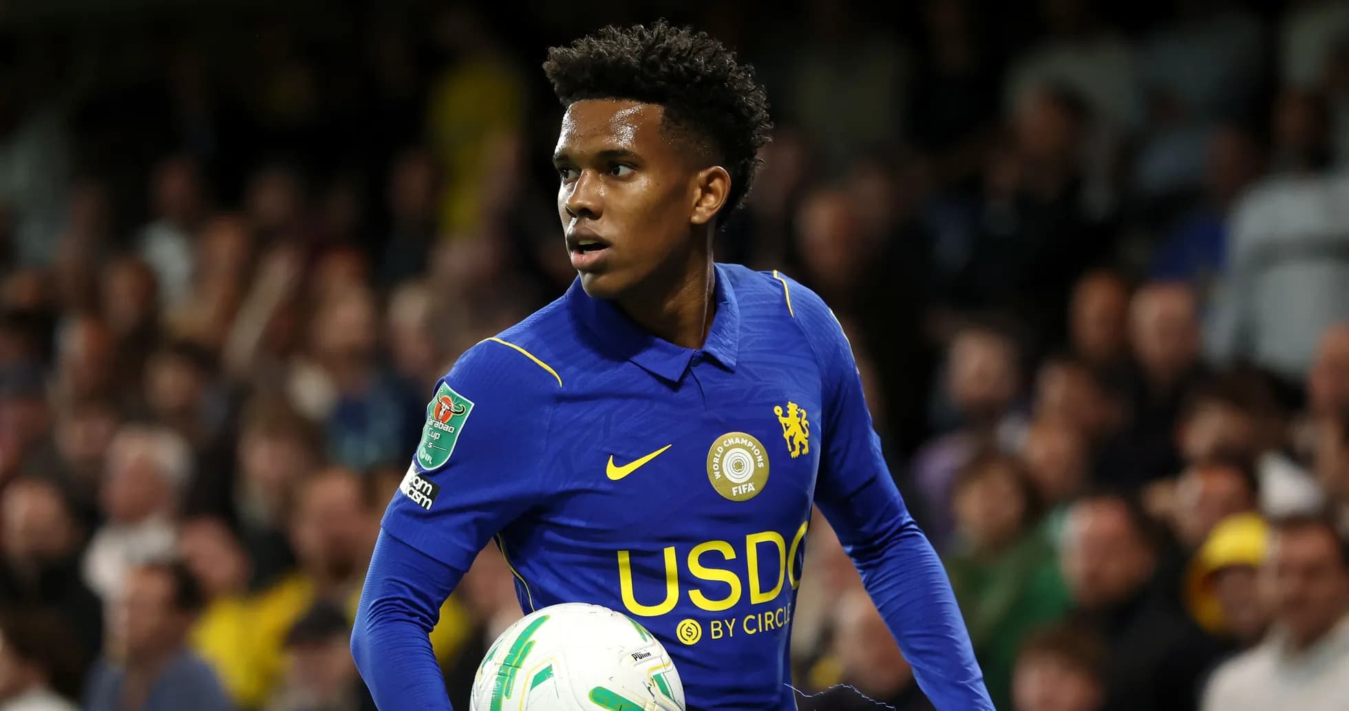 Player in blue kit holding a football on field