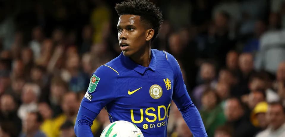 Player in blue kit holding a football on field