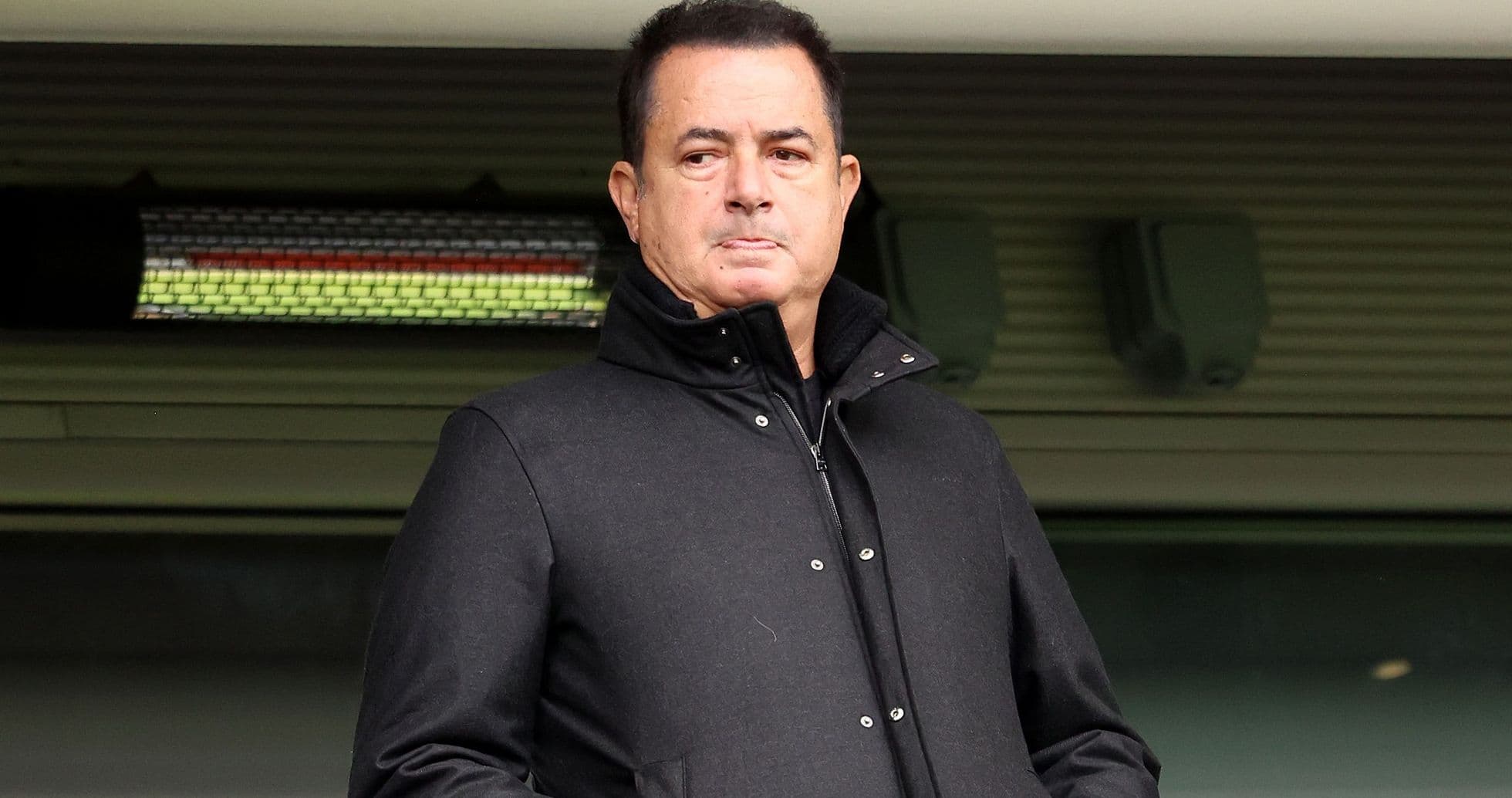Man in black coat standing in stadium box