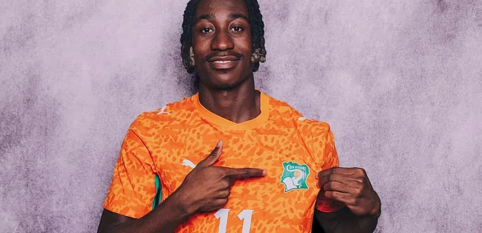 Player pointing at Côte d'Ivoire jersey emblem