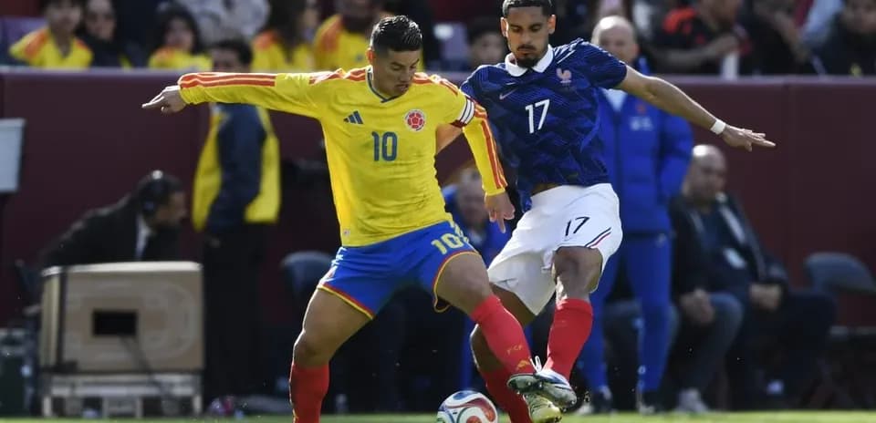 Colombian player dribbling past French opponent during match