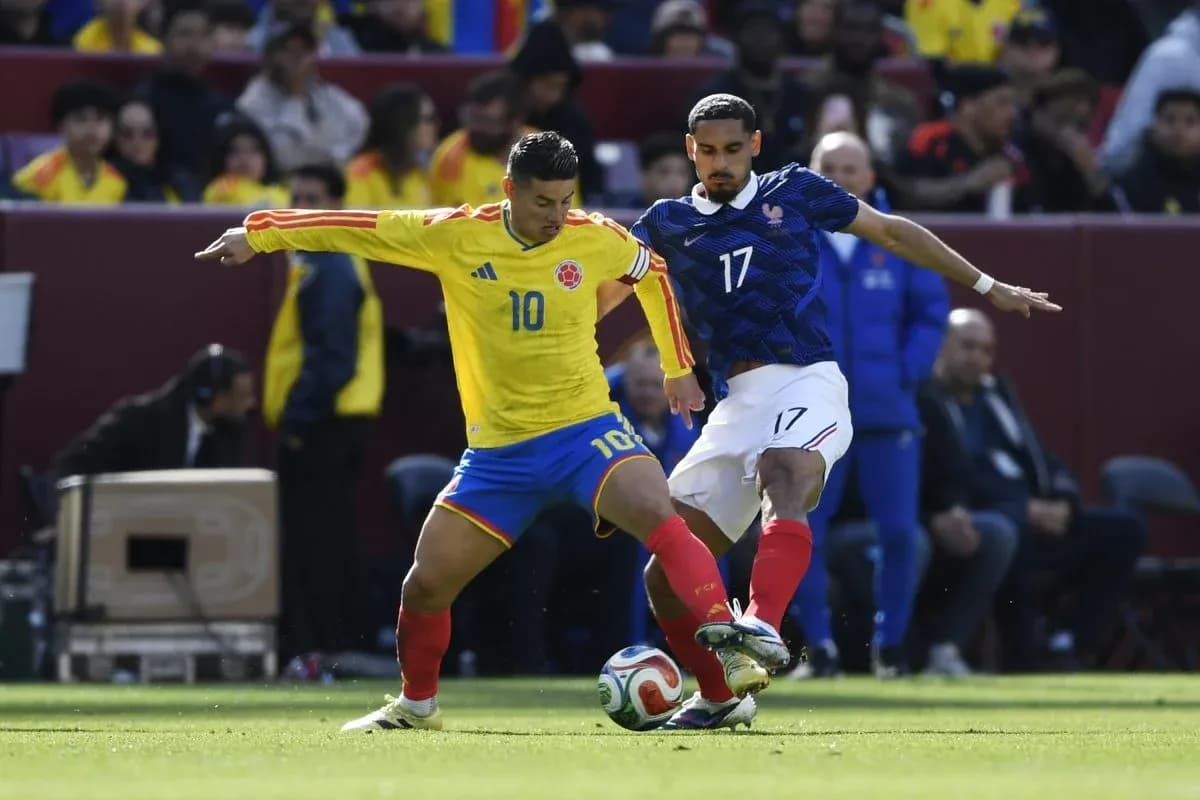 Colombian player dribbling past French opponent during match