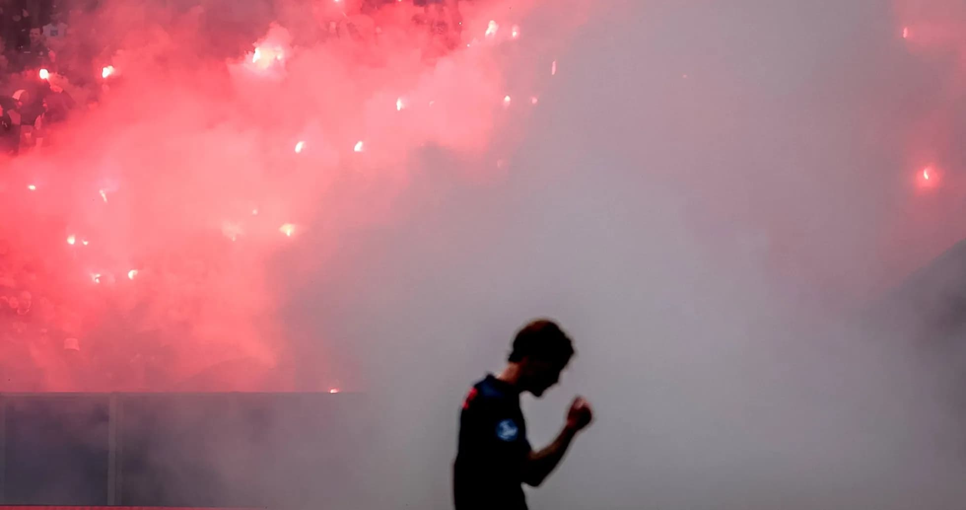 Player celebrating amid smoke and flares in stadium