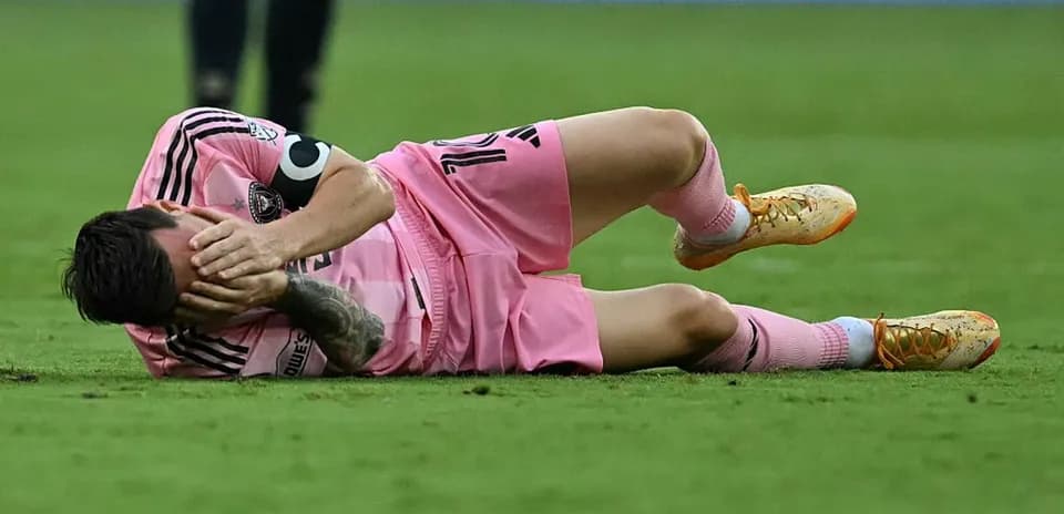 Player lying on ground, holding face in distress