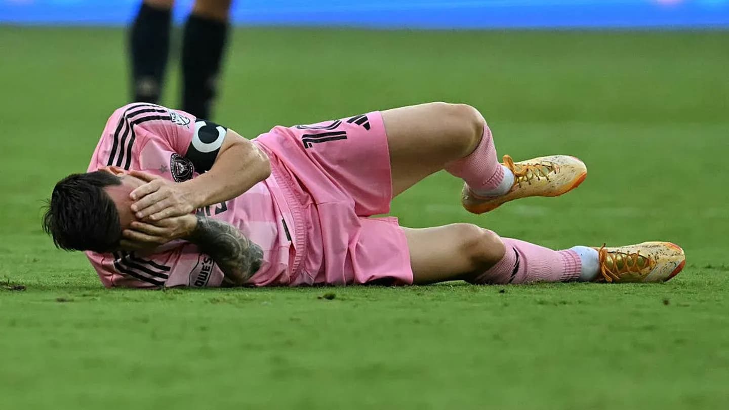 Player lying on ground, holding face in distress
