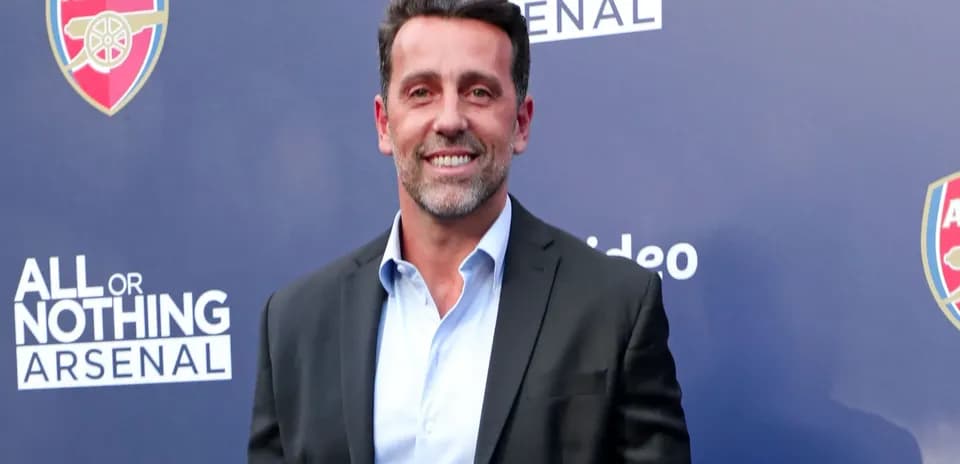 Man in suit smiling at Arsenal event backdrop