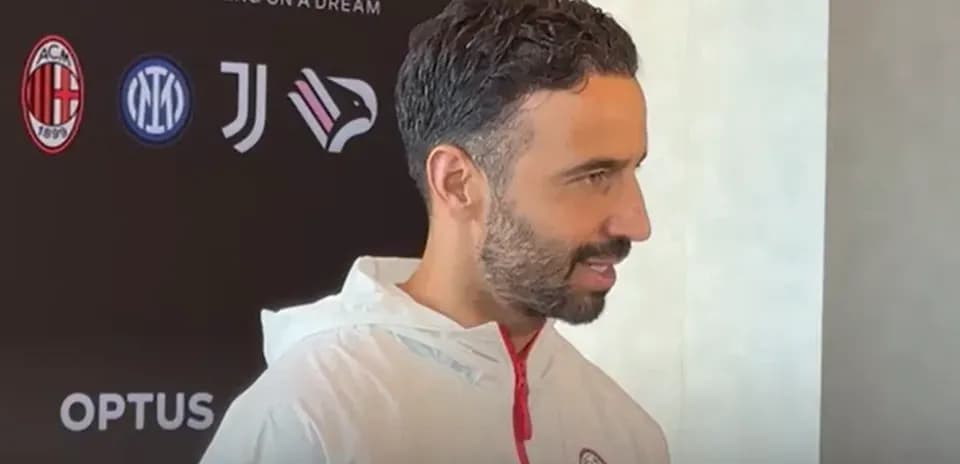 Person speaking at a press event with logos behind