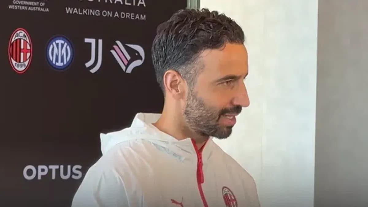 Person speaking at a press event with logos behind