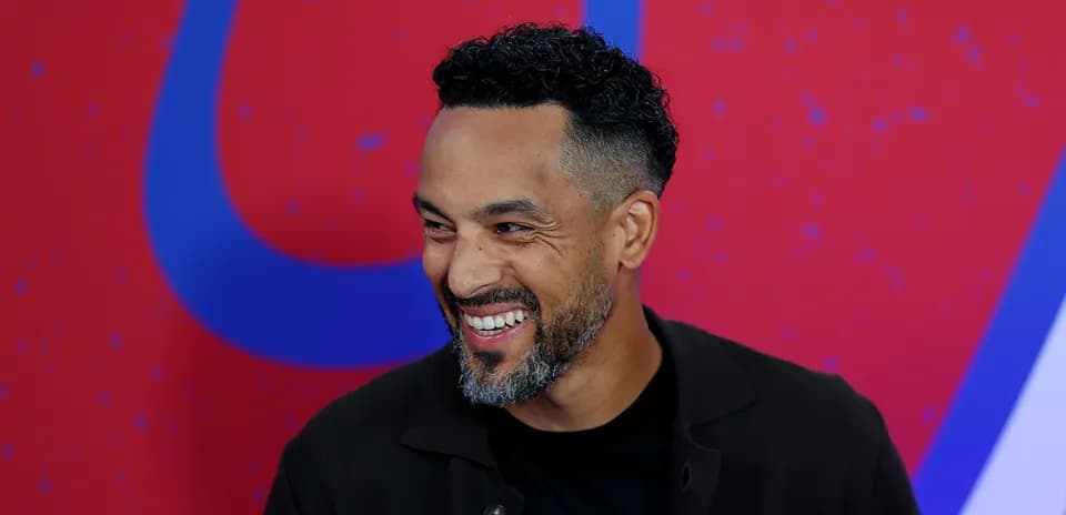 Man smiling during a press event with colorful background
