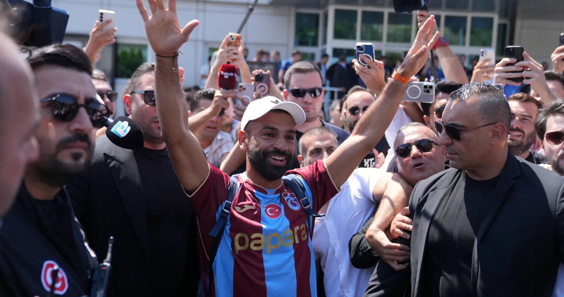 Player greeting fans surrounded by media and security