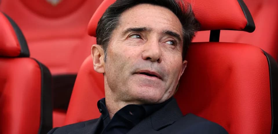 Coach seated on red bench during match