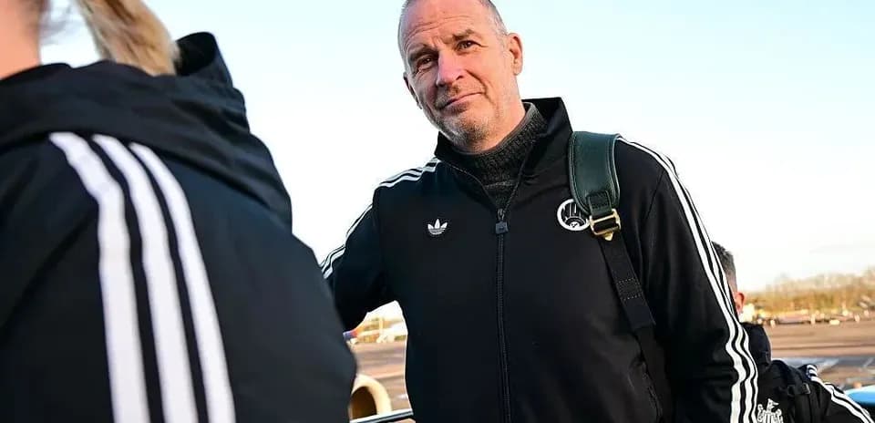 Coach in tracksuit at airport with team