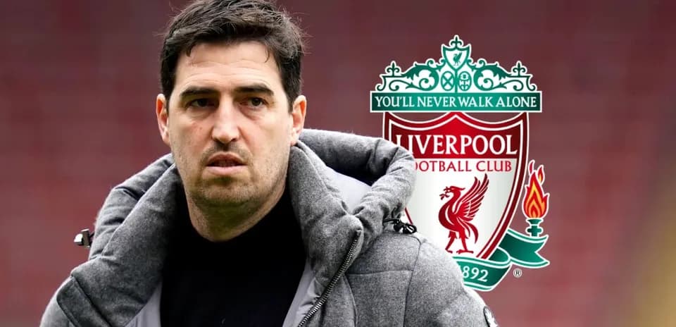 Man in jacket standing near Liverpool FC logo