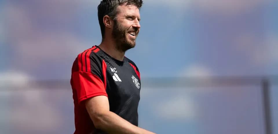 Coach walking on training pitch with Manchester United kit