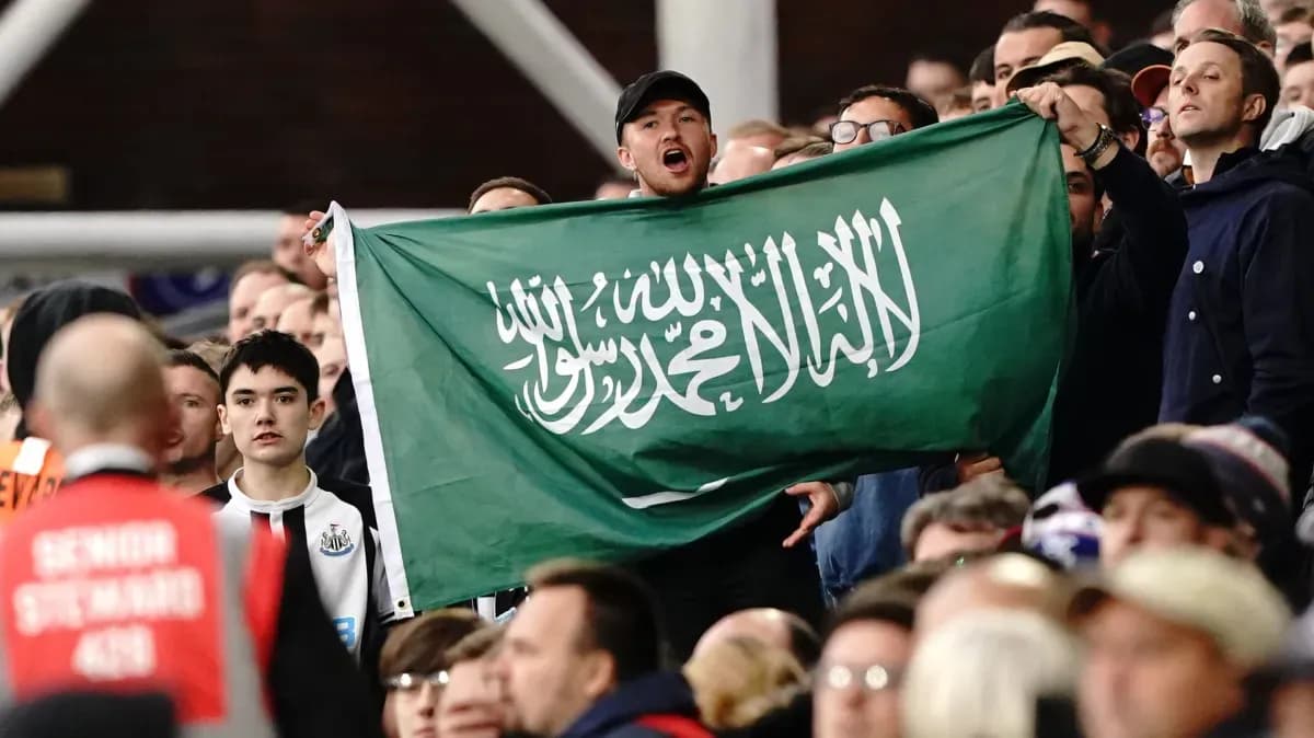 Fan holding Saudi Arabian flag in the stands Fan holding Saudi Arabian flag in the stands