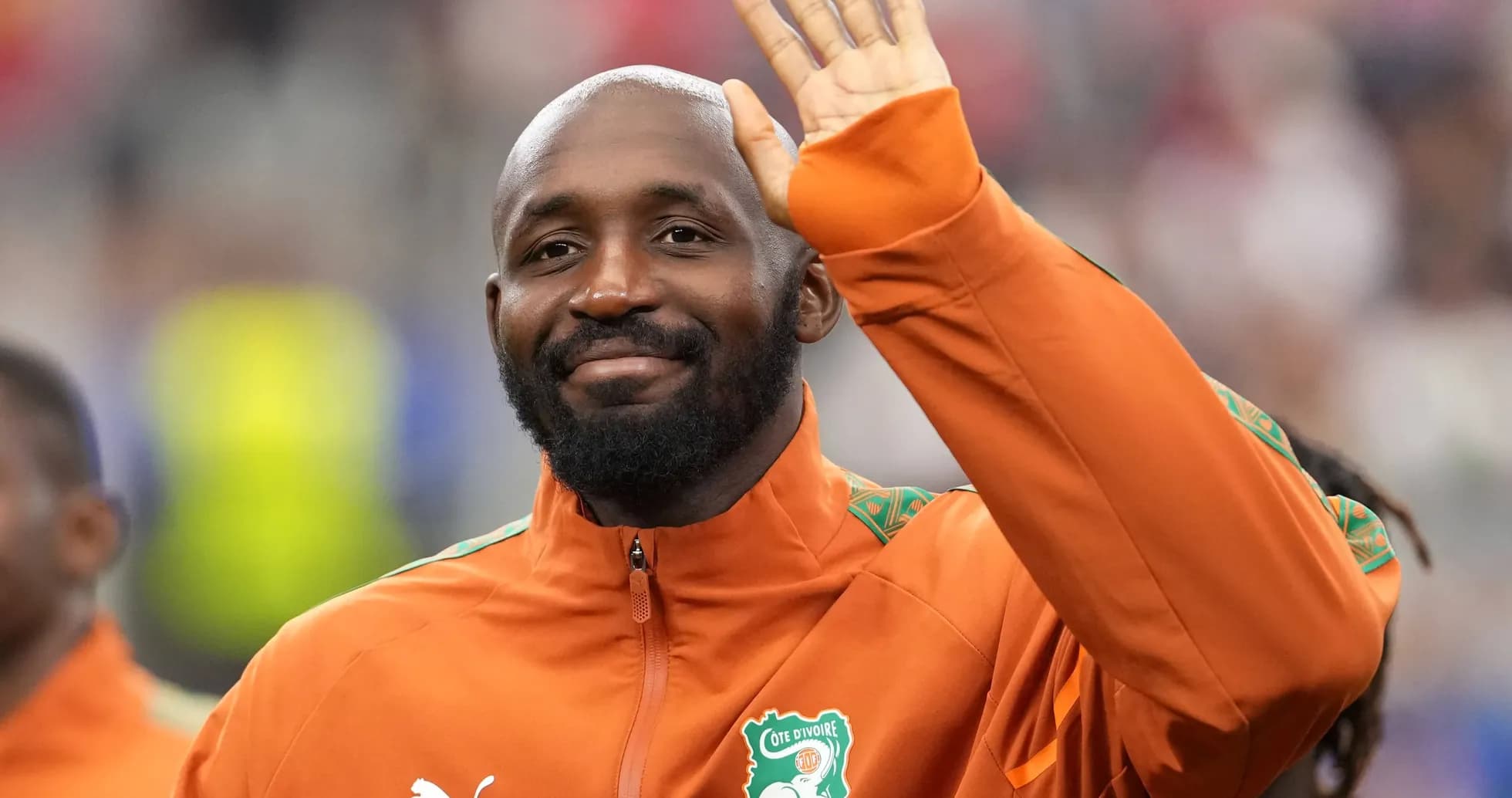 Player waving while wearing Ivory Coast training jacket Player waving while wearing Ivory Coast training jacket