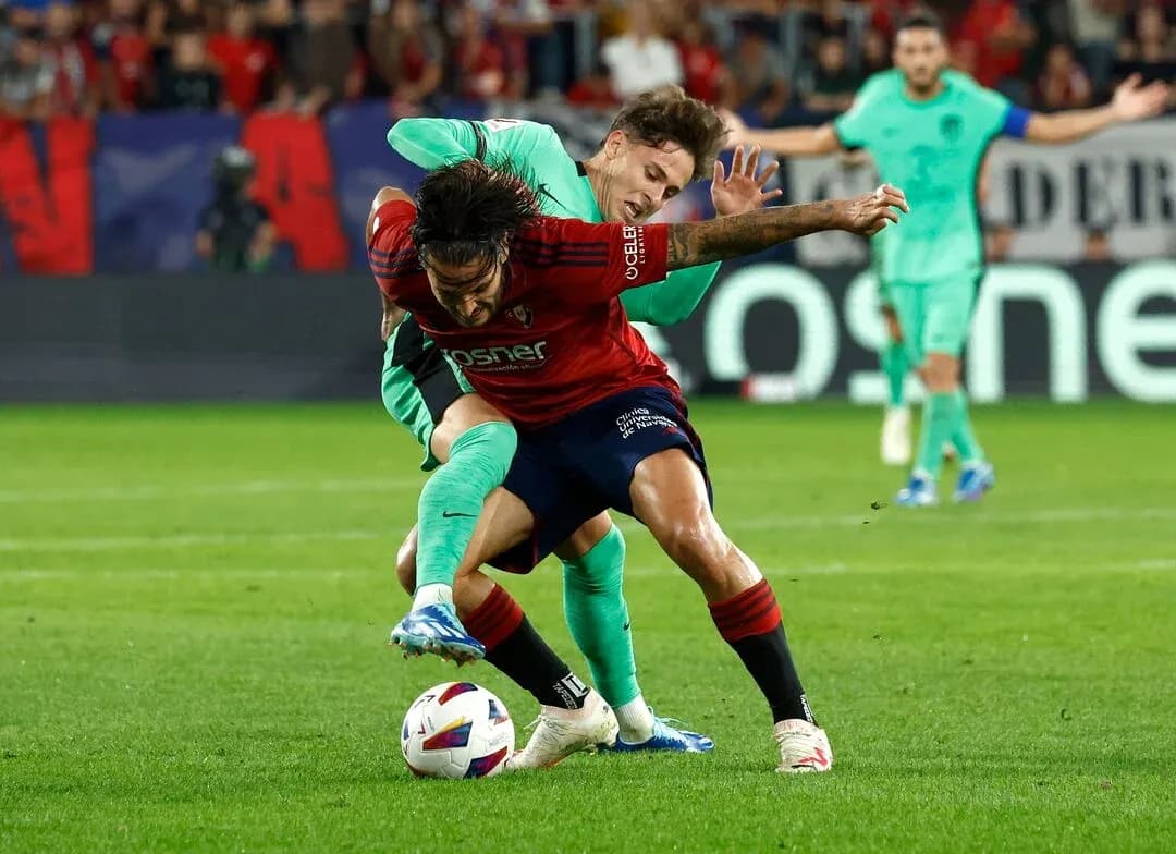 Osasuna player challenged by Atletico Madrid opponent Osasuna player challenged by Atletico Madrid opponent