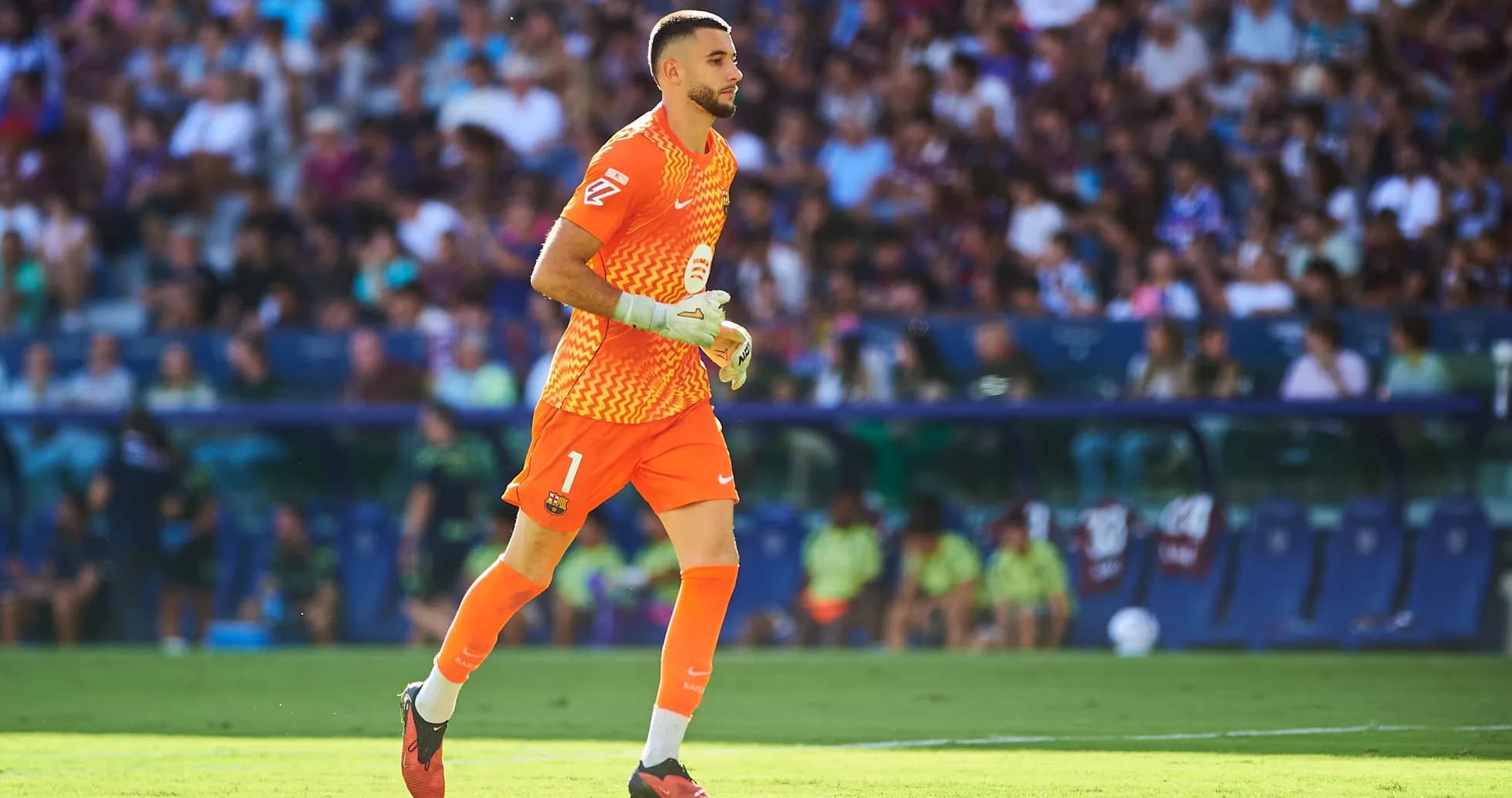 Goalkeeper in orange kit running on the field Goalkeeper in orange kit running on the field