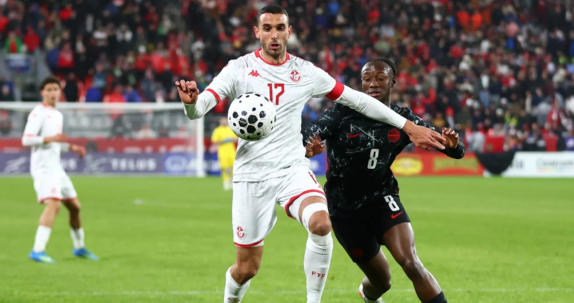Tunisian player controlling ball while opponent challenges Tunisian player controlling ball while opponent challenges