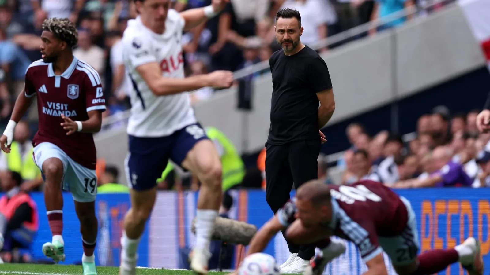 Aston Villa player running past Tottenham manager during match Aston Villa player running past Tottenham manager during match