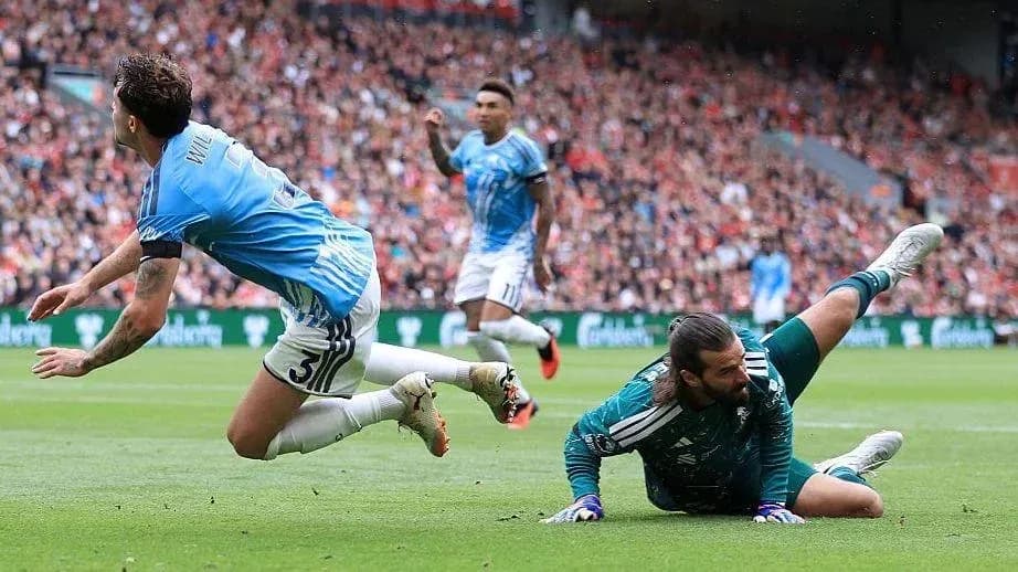 Player sliding past goalkeeper during a match Player sliding past goalkeeper during a match
