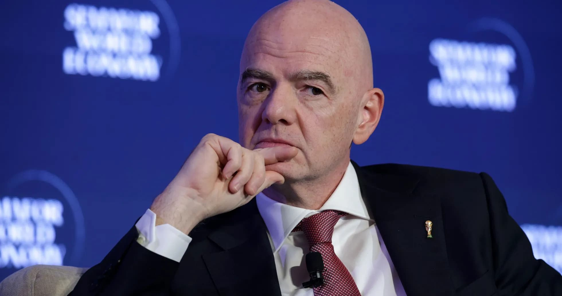 Man speaking at a conference with FIFA logo pin Man speaking at a conference with FIFA logo pin