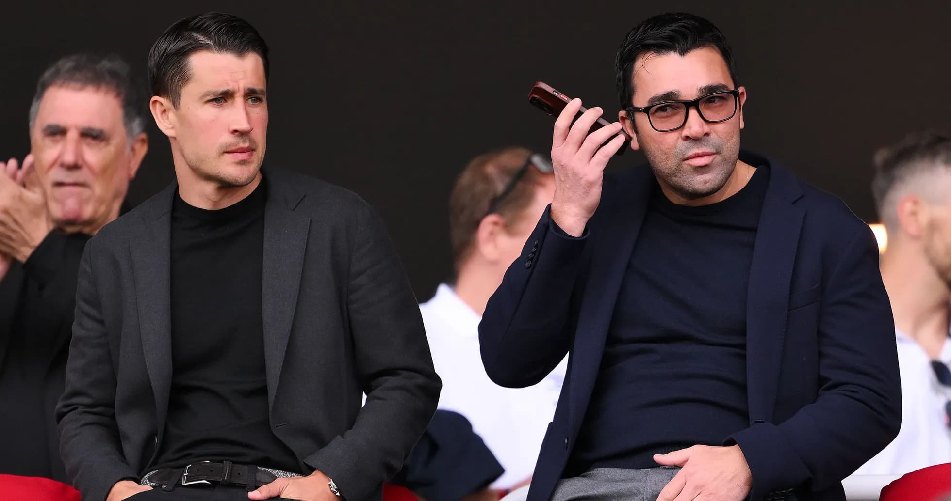Two men seated in the stands during an event Two men seated in the stands during an event