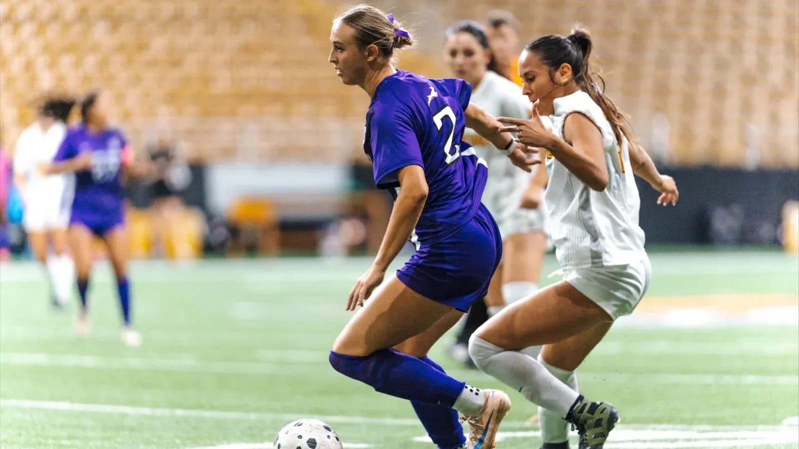 Two female players competing for the soccer ball Two female players competing for the soccer ball