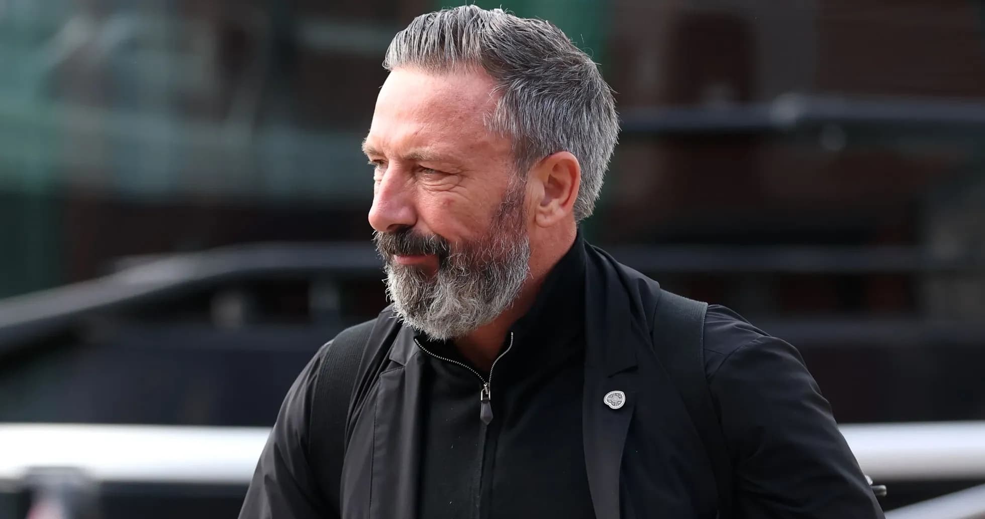 Man with beard walking past a bus Man with beard walking past a bus