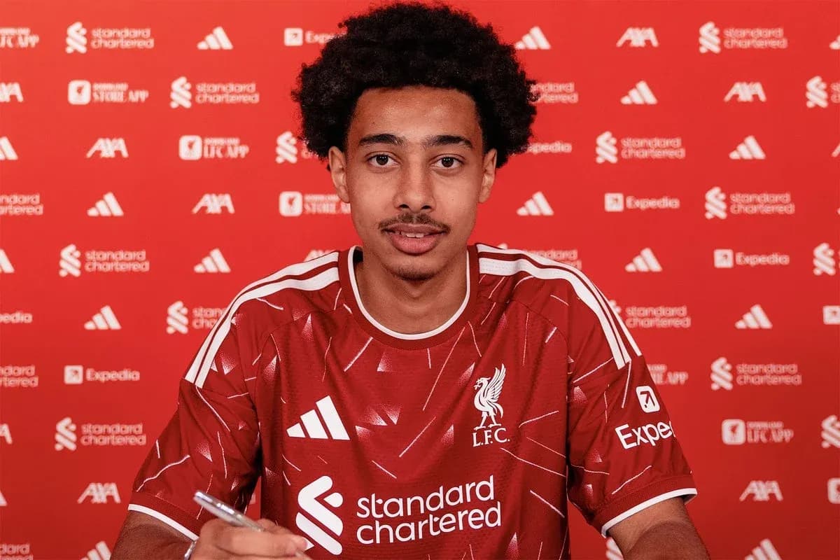 Player signing contract in Liverpool jersey at table Player signing contract in Liverpool jersey at table