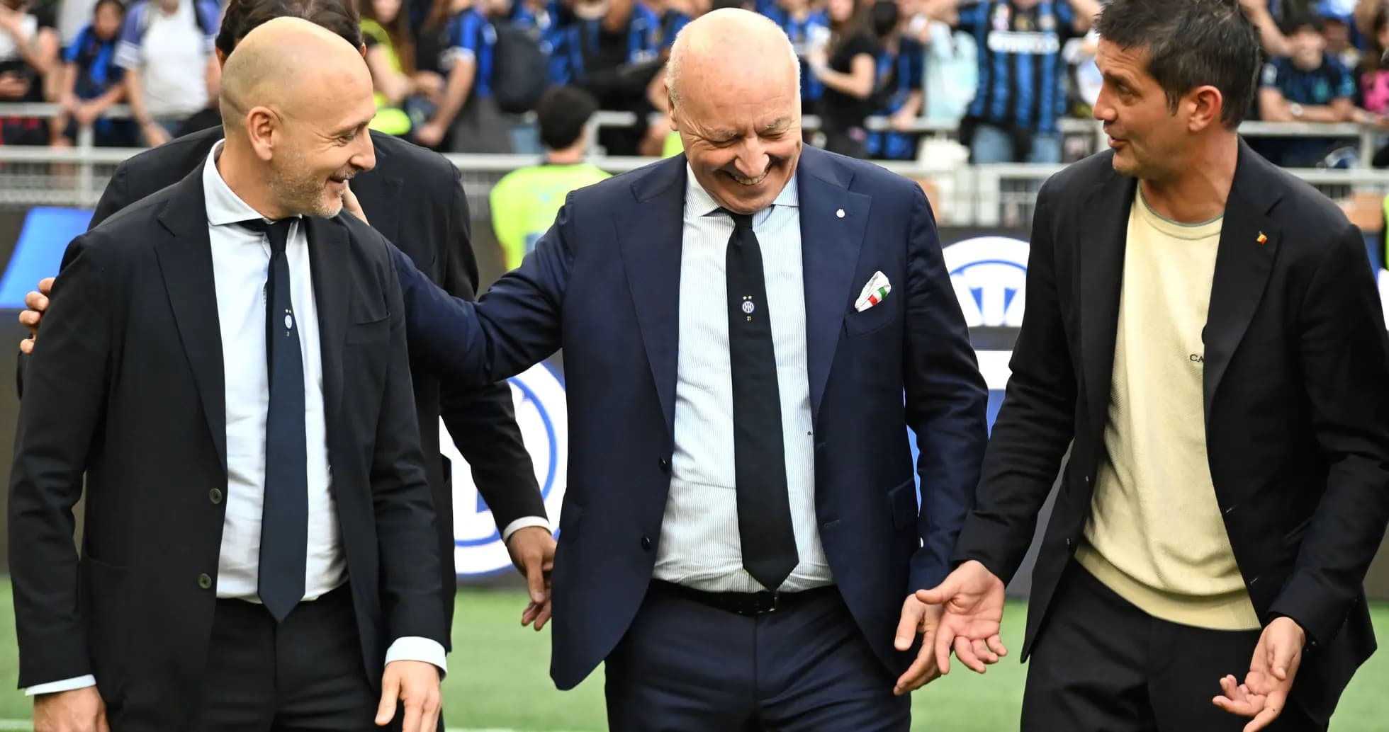 Three coaches interacting on the pitch before a match Three coaches interacting on the pitch before a match