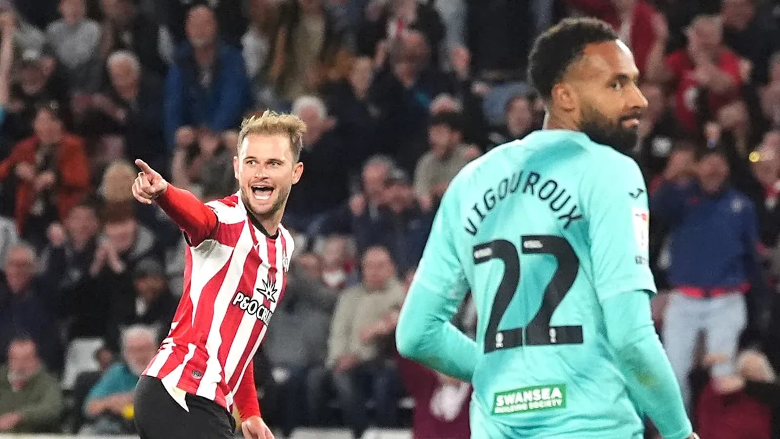 Player celebrating a goal while opponent looks on Player celebrating a goal while opponent looks on