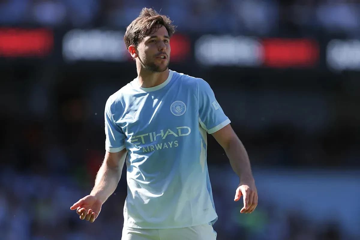 Player in light blue Manchester City jersey on pitch Player in light blue Manchester City jersey on pitch