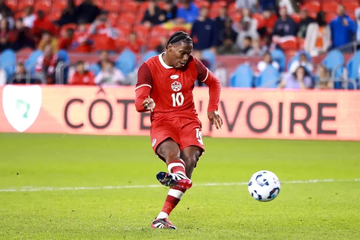 Player in red jersey kicking a soccer ball Player in red jersey kicking a soccer ball