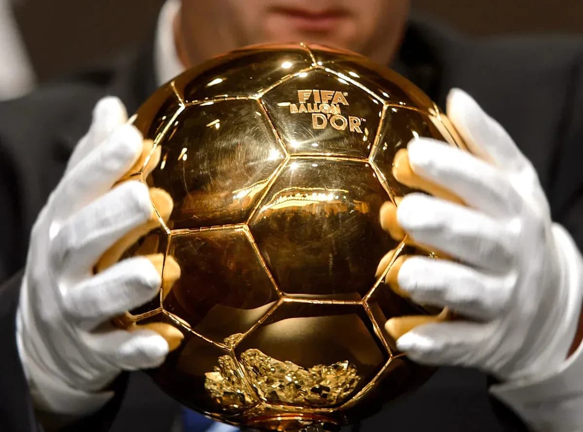 Person holding FIFA Ballon d'Or trophy with gloves Person holding FIFA Ballon d'Or trophy with gloves