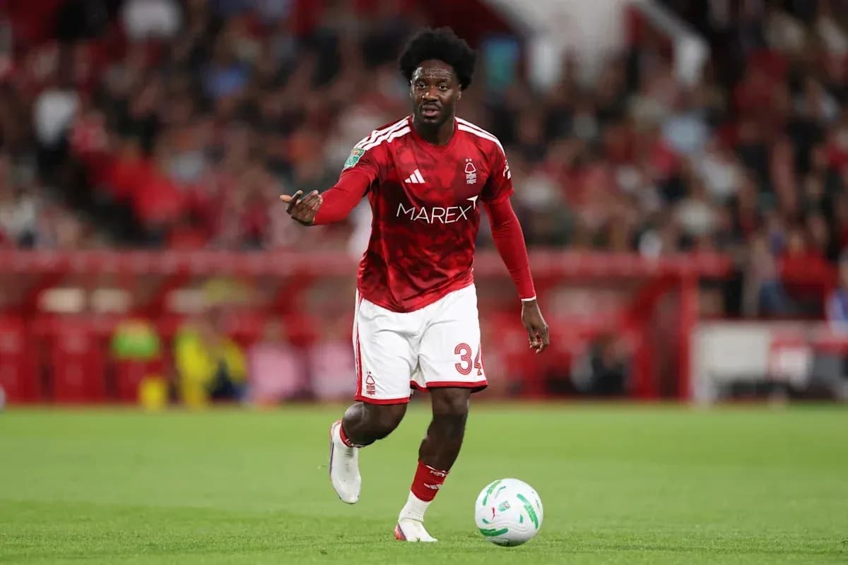 Player in red kit dribbling ball on field Player in red kit dribbling ball on field