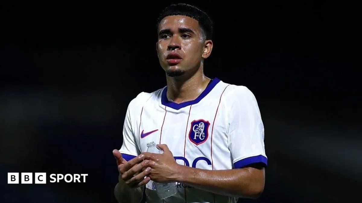 Player in white jersey holding water bottle on pitch Player in white jersey holding water bottle on pitch