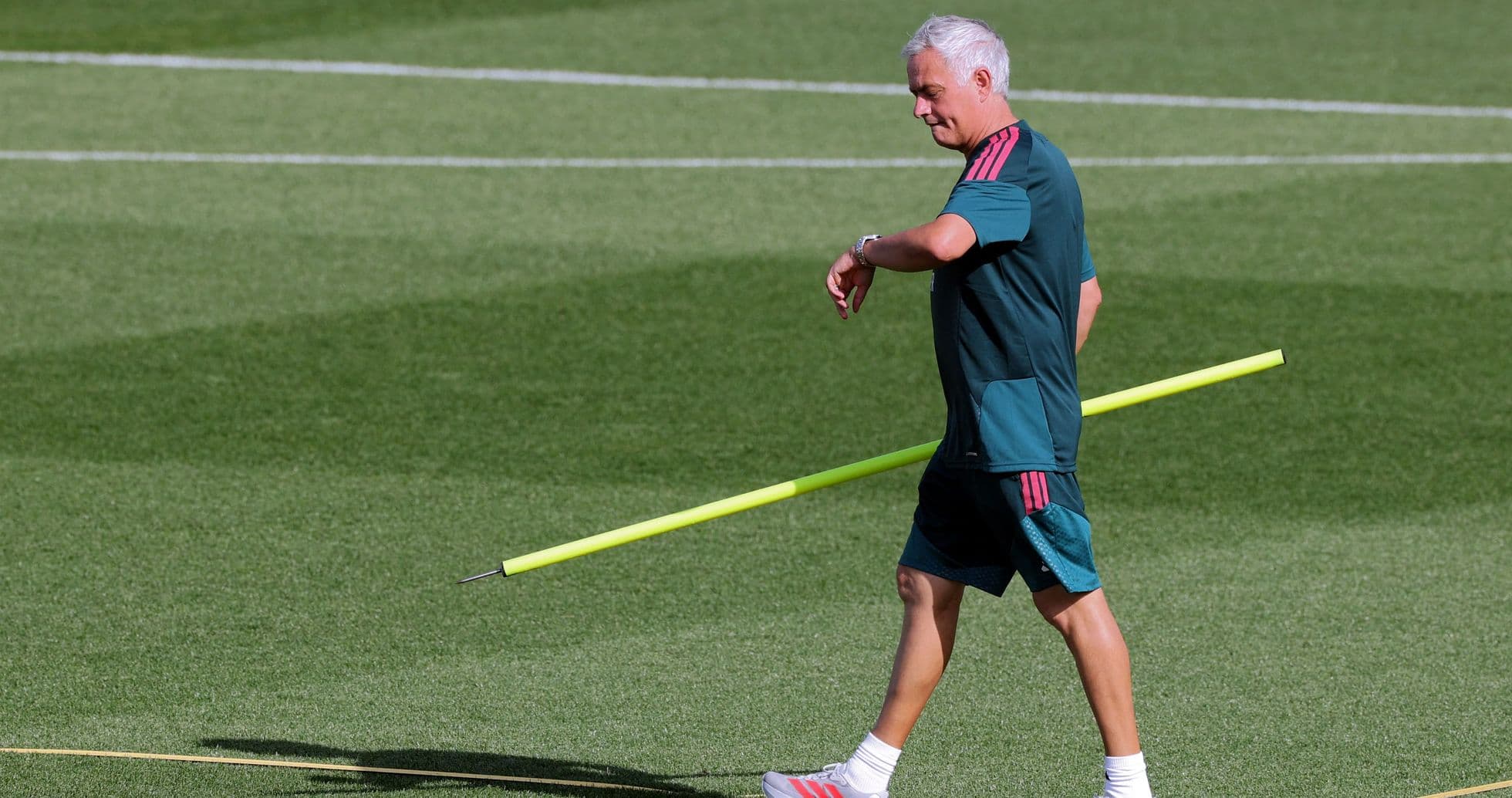 Coach walking on training pitch with equipment Coach walking on training pitch with equipment